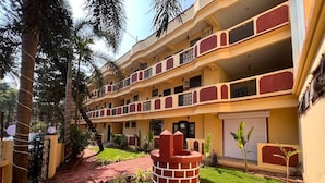 Un hôtel à plusieurs étages doté d’une cour intérieure, construit en briques et possédant une pelouse bien entretenue.