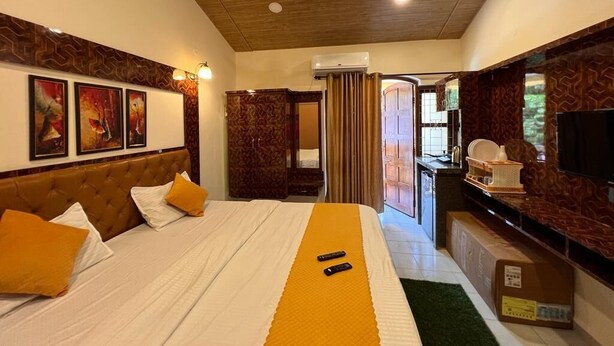 Une chambre d’hôtel avec un lit, un ventilateur de plafond, des œuvres d’art accrochées au mur et un téléviseur.