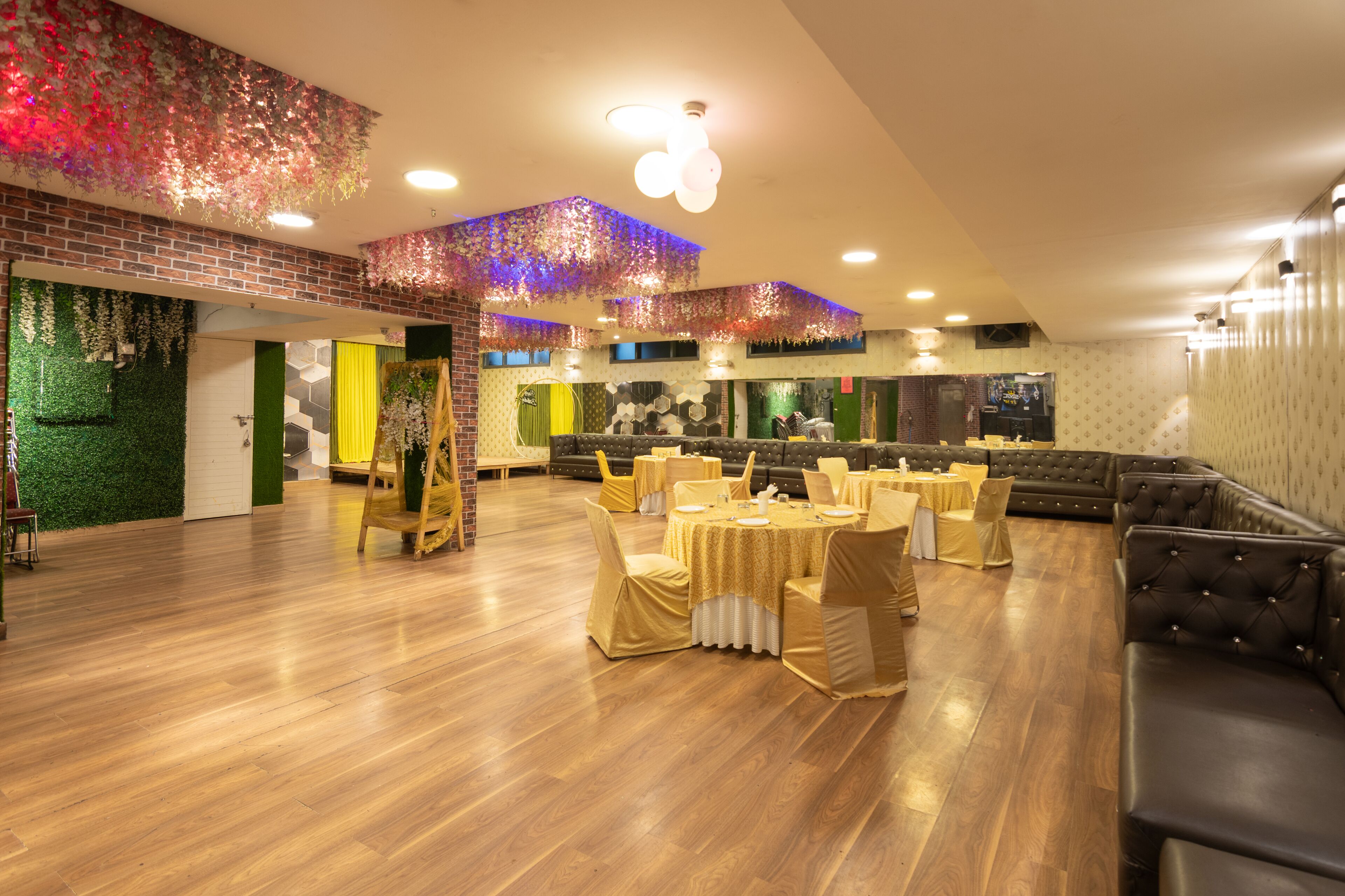 A spacious room with wooden flooring, round tables with yellow tablecloths, and leather seating.