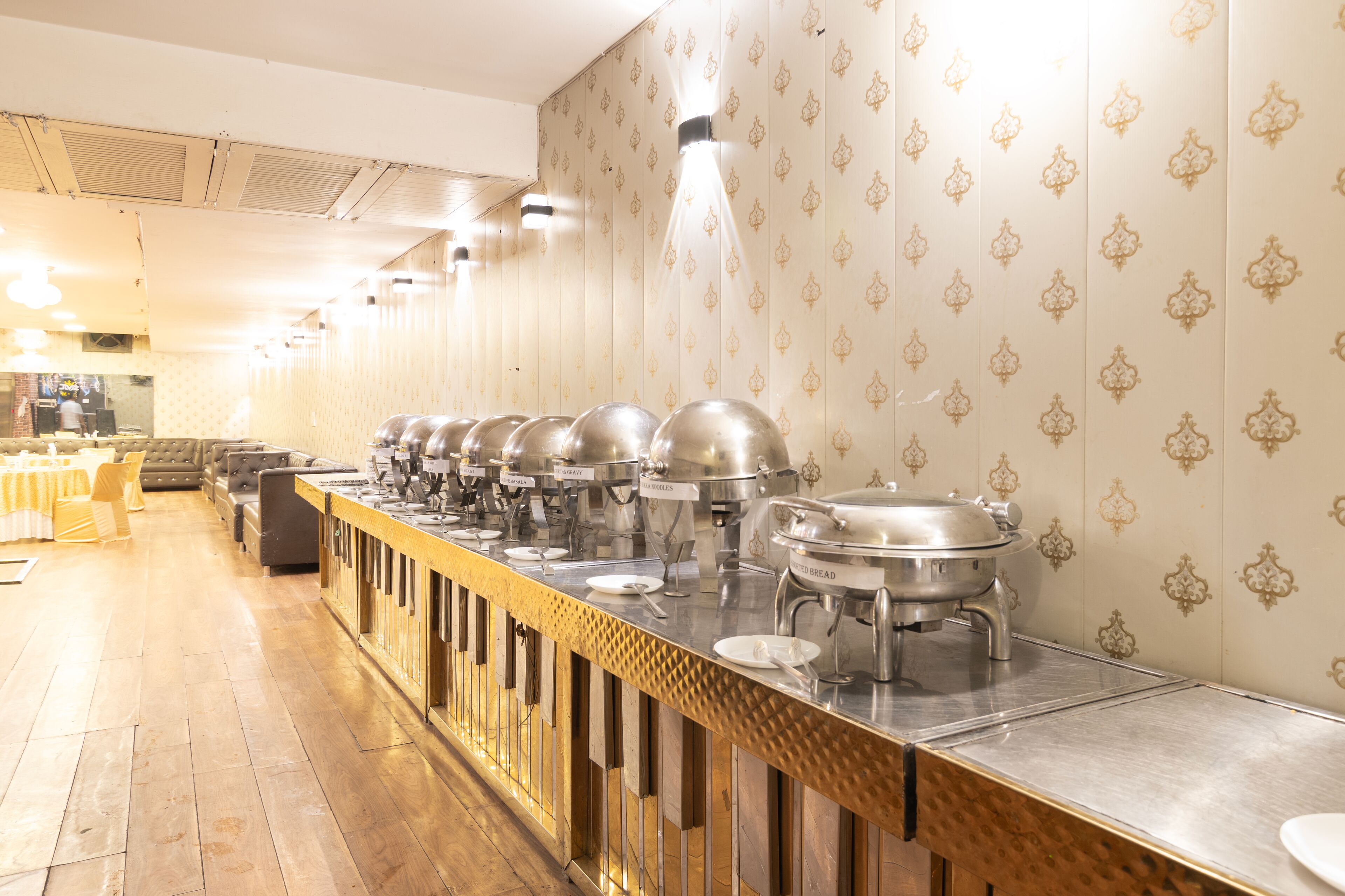 A buffet setup with multiple serving stations, a long counter, and a patterned wall.