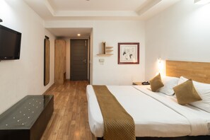Ein Hotelzimmer mit Bett, Nachttisch, Fernseher, Holzschrank und einem gerahmten Bild an der Wand.