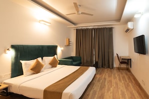Ein Hotelzimmer mit Bett, Schreibtisch, Stuhl, Deckenventilator und Klimaanlage.