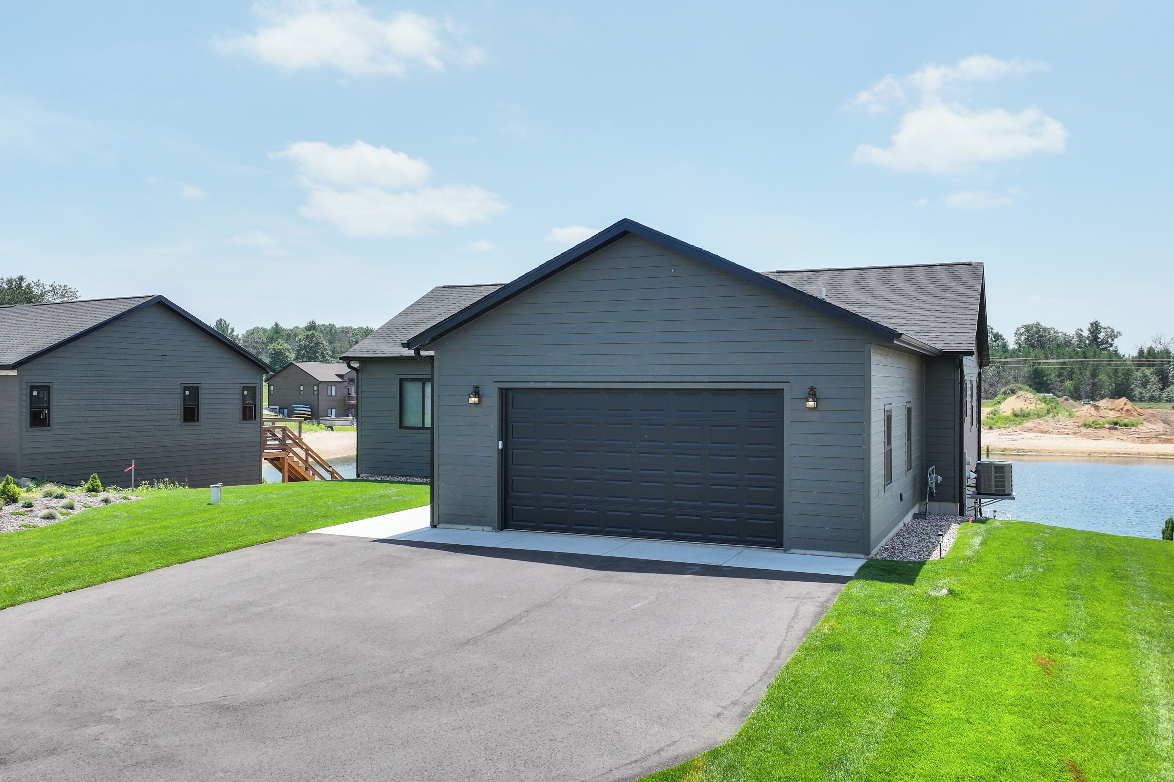 Ein modernes, zweistöckiges Haus mit großer Garage, gepflegtem Rasen und Seeblick.