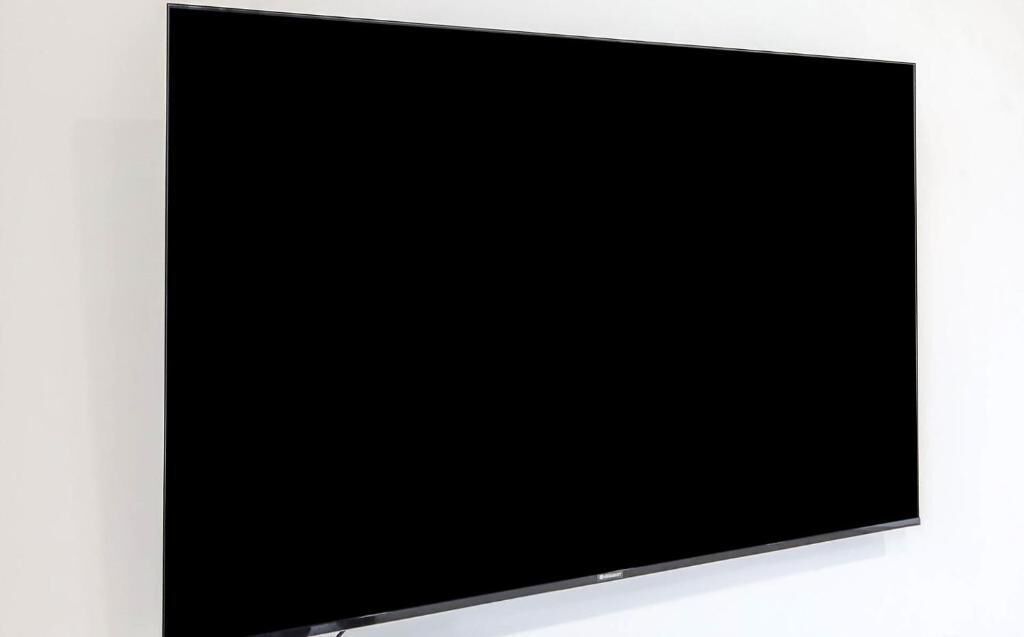 Un televisor de pantalla plana grande montado sobre una pared blanca.