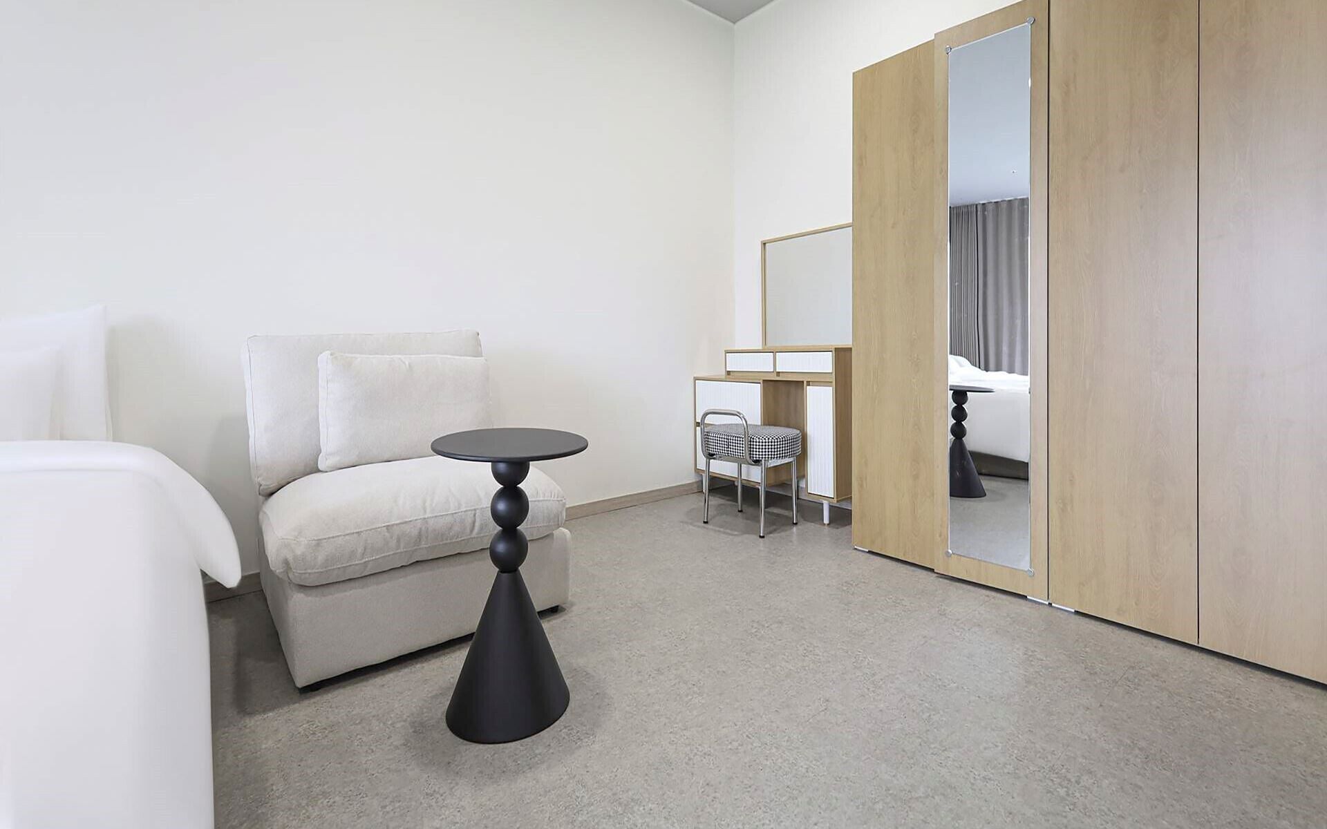 Habitación de hotel con cama, una mesita redonda, una silla, armario y espejo.