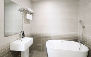 A modern bathroom with a freestanding bathtub, a sink, and a mirror.