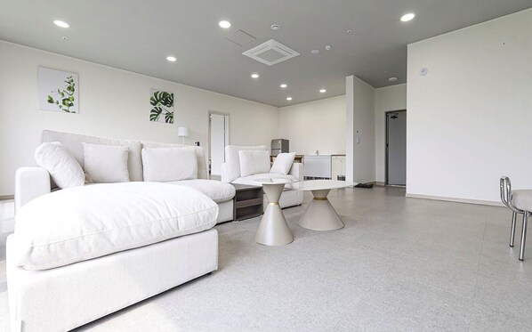 Una habitación de hotel moderna con una cama grande, una mesa redonda y una pequeña kitchenette.