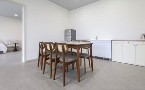 A room with a dining table and chairs, a kitchenette, a bed, and a sofa.