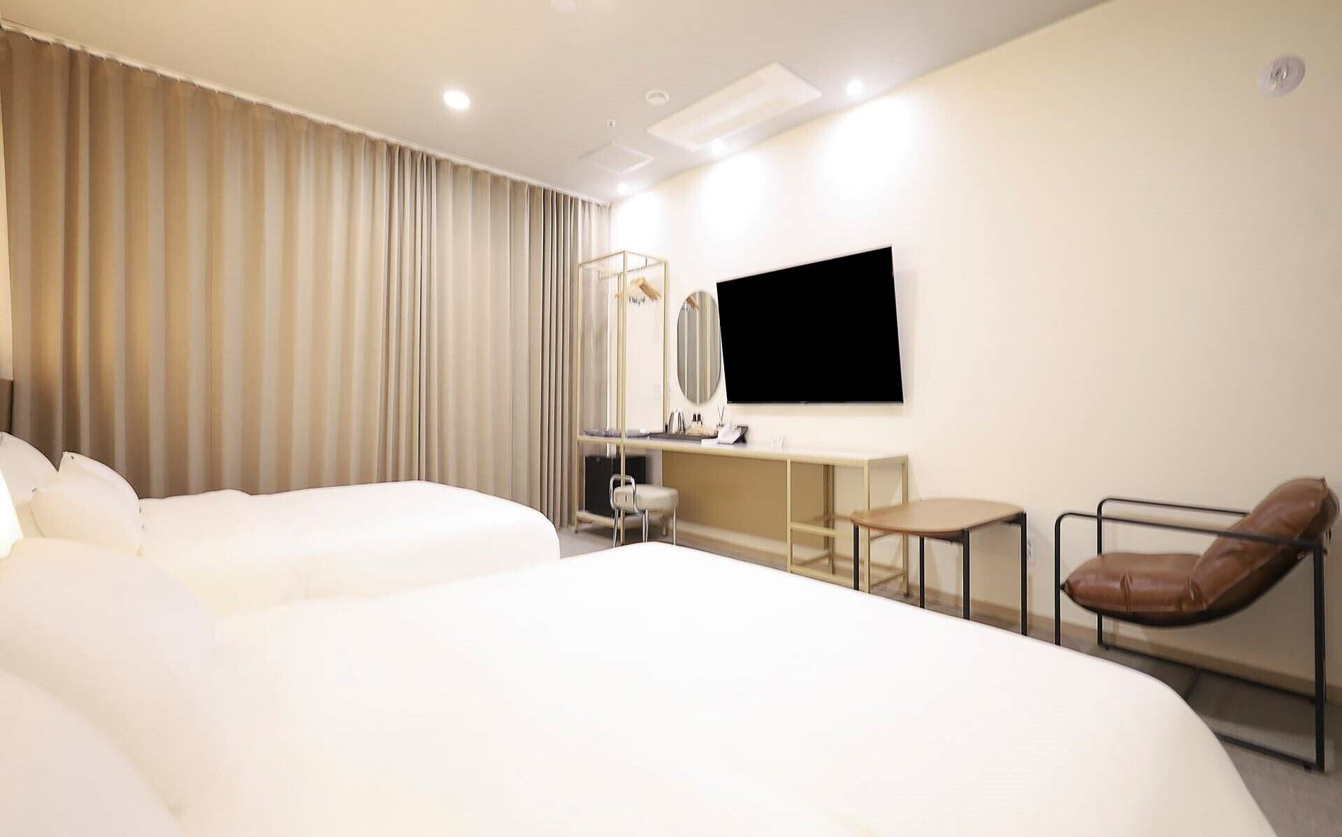 A hotel room with a large bed, a desk, a chair, and a TV.