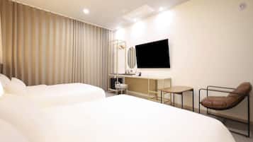 A hotel room with a large bed, a desk, a chair, and a TV.