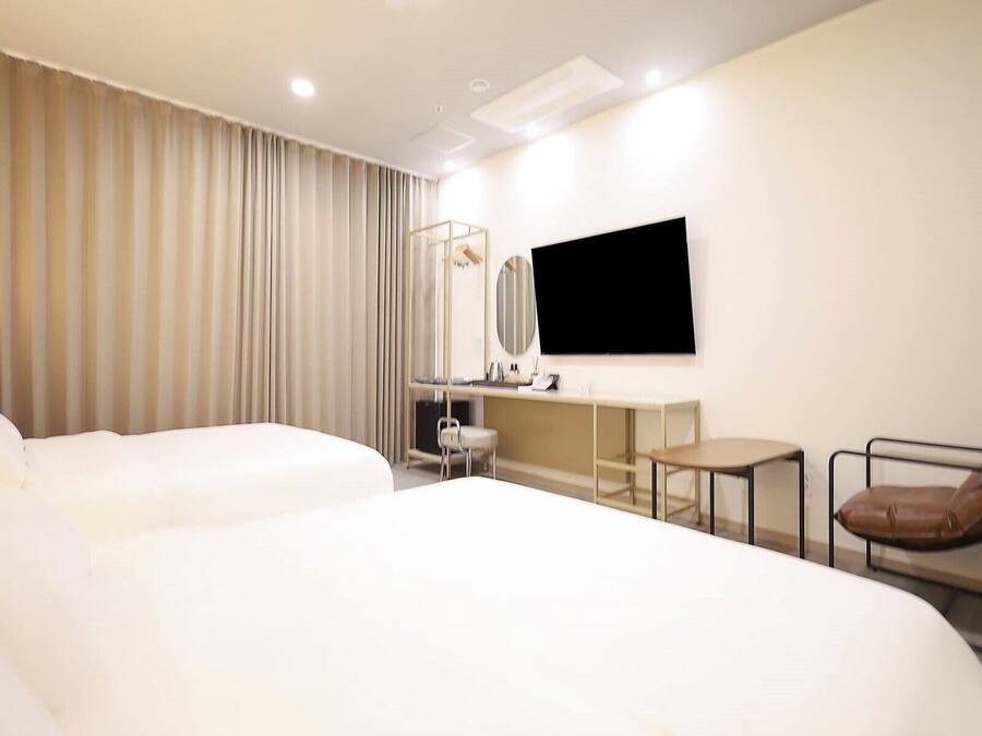 A hotel room with a large bed, a desk, a chair, and a TV.