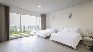 Habitación de hotel con dos camas, un ventanal con vistas y un balcón.