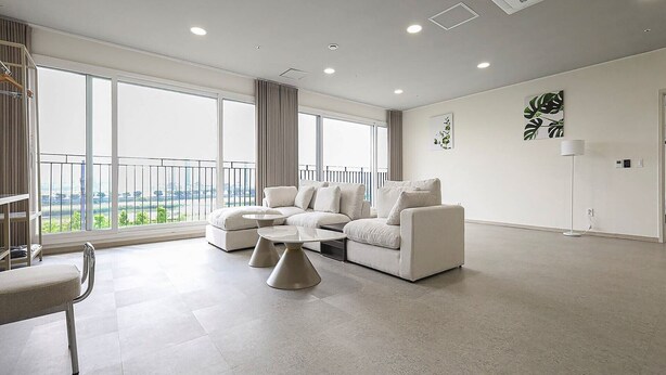 Un salón moderno con un sofá modular, una mesita de centro y vistas a un paisaje urbano a través de amplias ventanas.