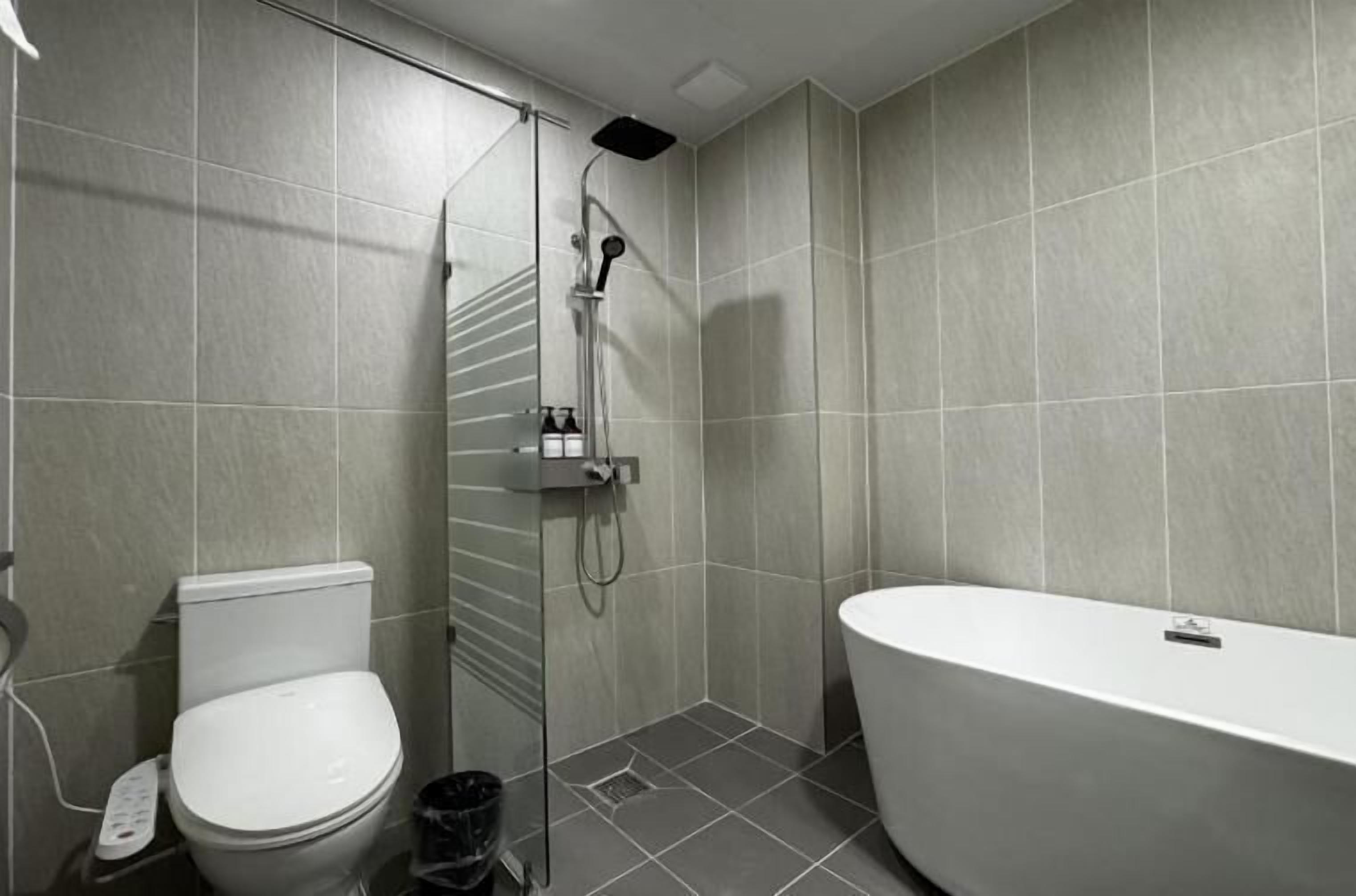 A modern bathroom with a toilet, a shower, and a bathtub.
