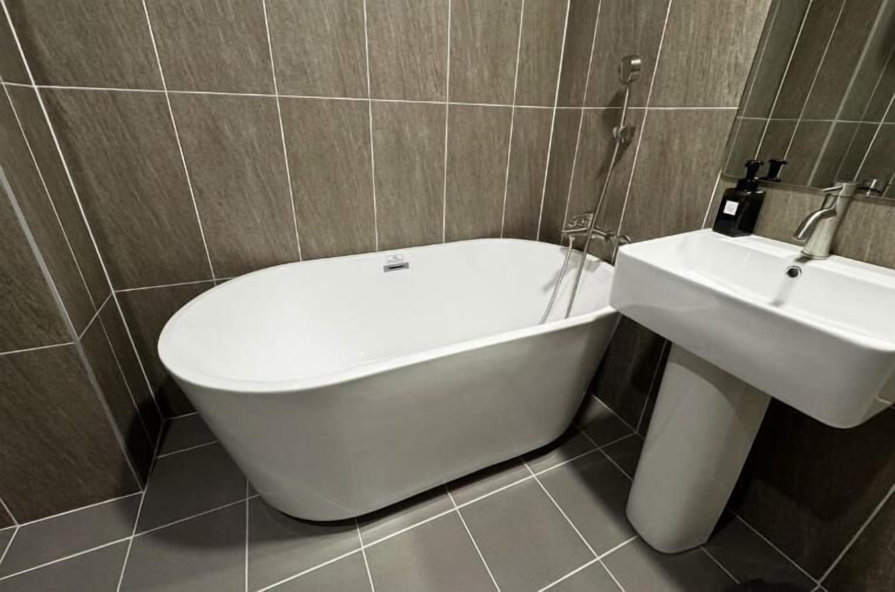 A modern bathroom with a freestanding bathtub, a pedestal sink, and a showerhead.