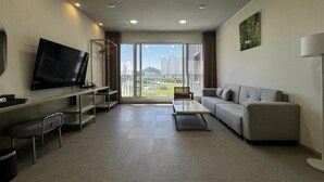 Una sala de estar moderna con un sofá, una mesa de centro, un televisor y un balcón con vistas a la ciudad.