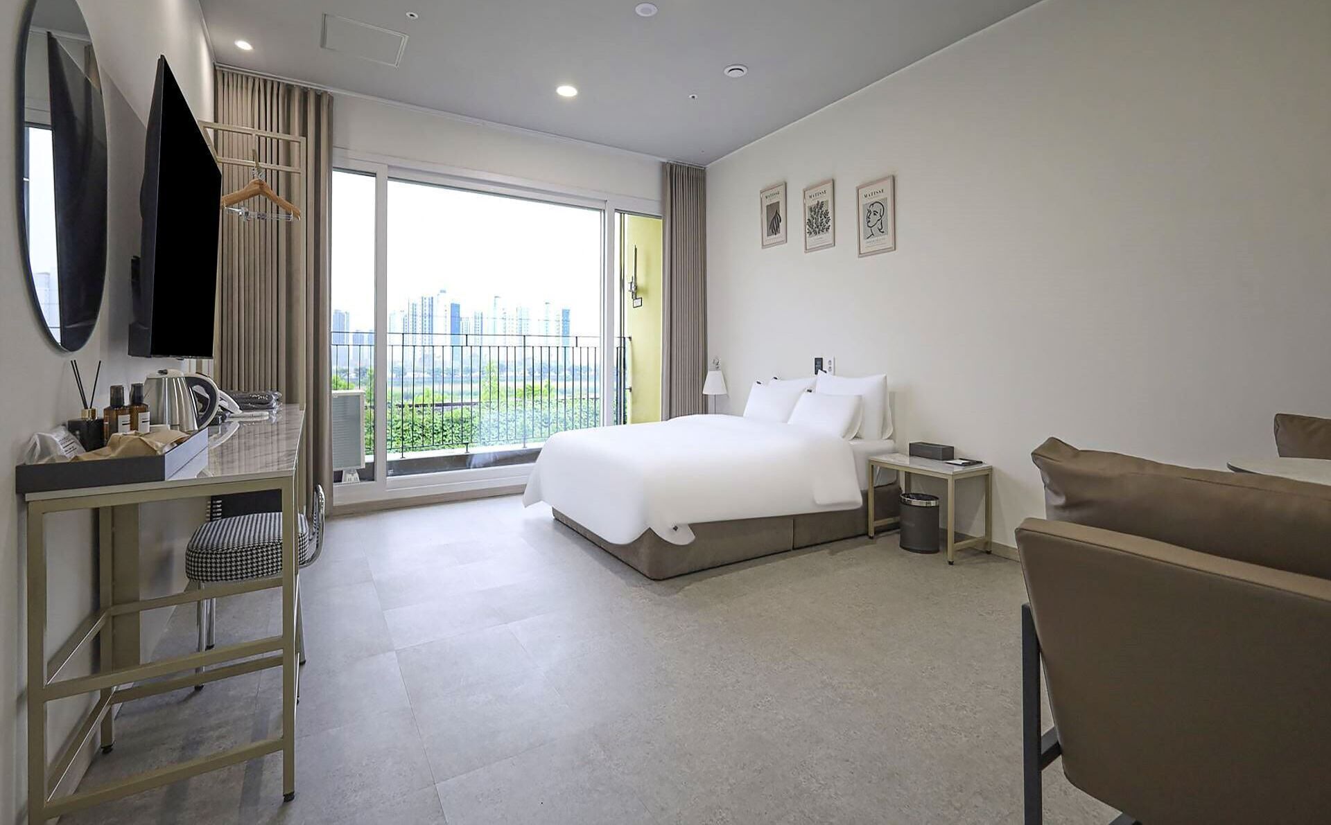 Habitación de hotel con cama, escritorio, silla, televisor y ventana con vista a la ciudad.