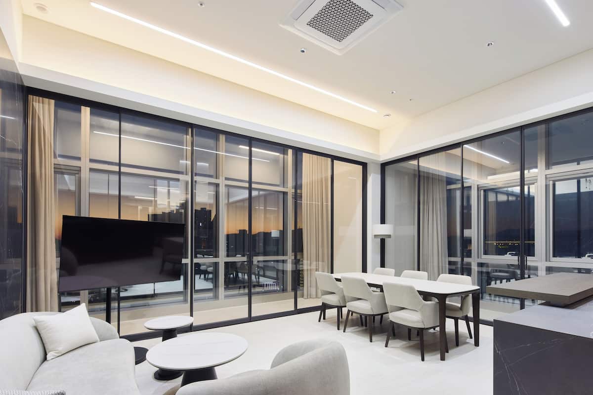 A modern hotel lobby with a large TV, comfortable seating, and large windows offering city views.