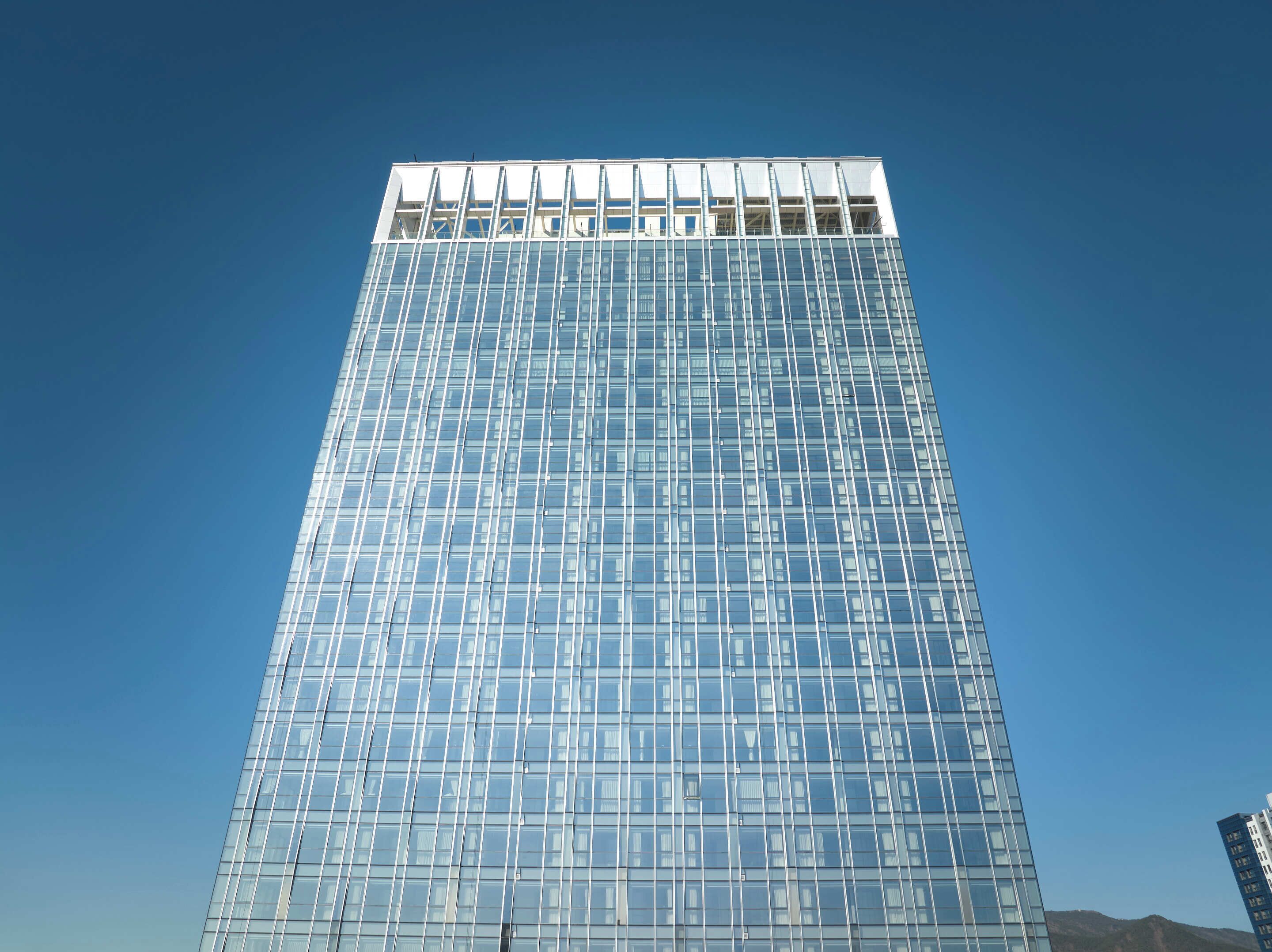 A tall, modern glass building with a grid-like facade and a flat roof.