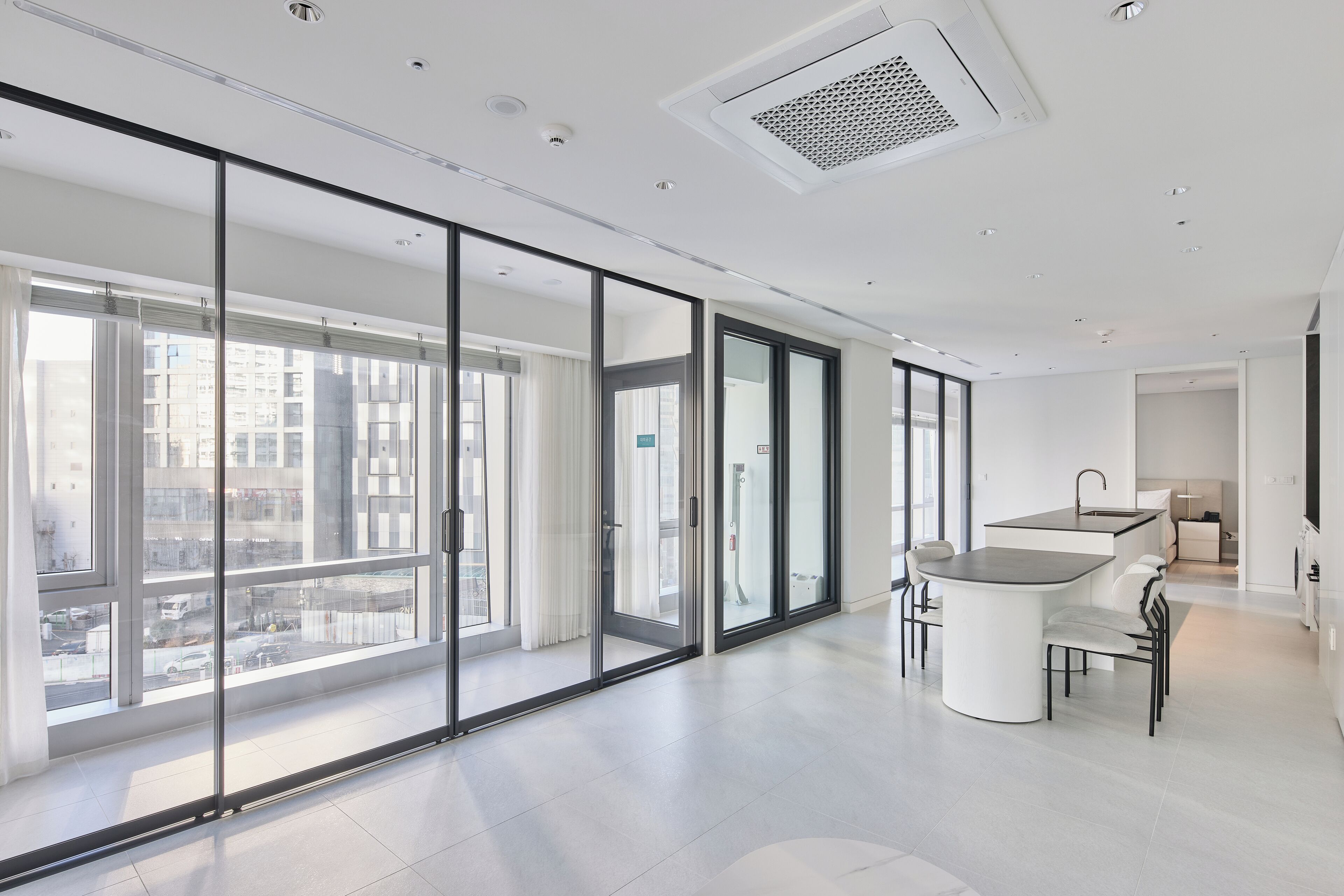 Un apartamento moderno con amplios ventanales correderos, una cocina con una isla central y vistas a la ciudad.
