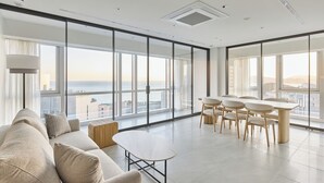 Ein modernes Wohnzimmer mit einer großen Couch, einem Couchtisch und einem Essbereich mit Stühlen und einem Tisch.