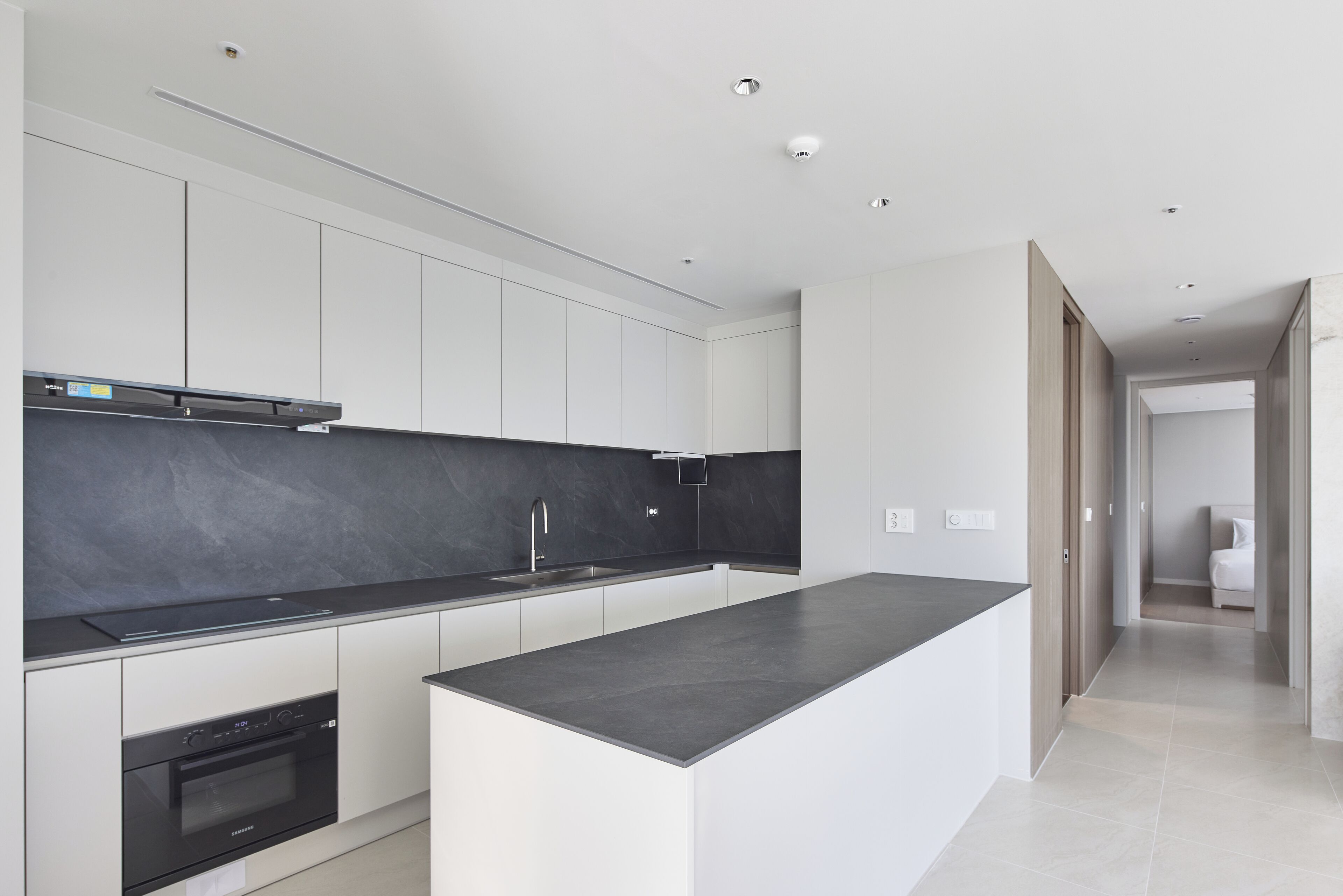 A modern kitchen with a large island, built-in oven, and sleek cabinetry.