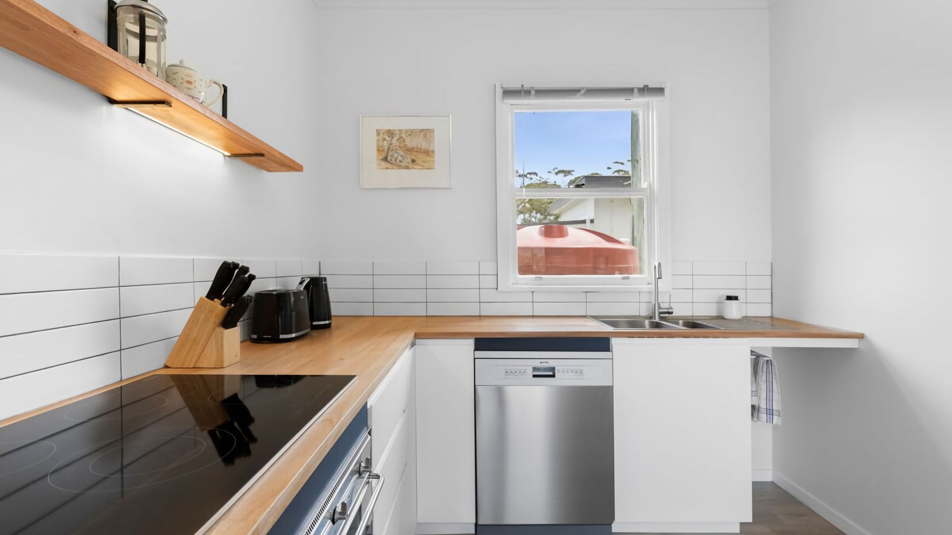 A modern kitchen with a dishwasher, a coffee maker, and a knife block.