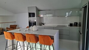 A modern kitchen with a central island, bar stools, and a dining table. - family and groups escape with  views , sunrise and sunsets in a quiet corner  (Calheta)