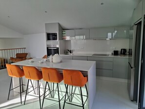 Una cocina moderna con una isla central, taburetes de bar y una mesa de comedor.
