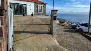 A residential property with a stone facade, a red-tiled roof, and a view of the sea. - family and groups escape with  views , sunrise and sunsets in a quiet corner  (Calheta)