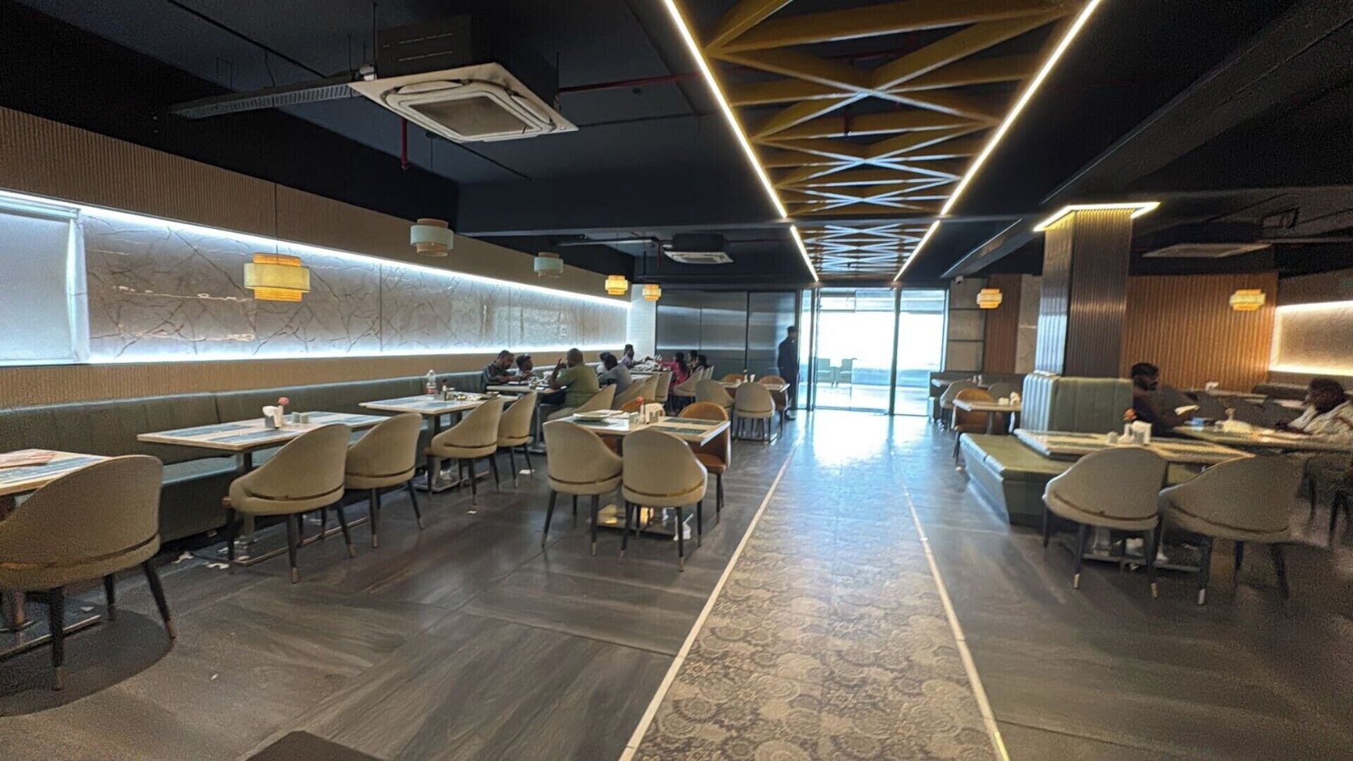 Un comedor espacioso con techos altos, iluminación moderna y un pasillo central.