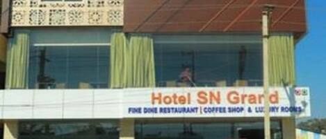 A building with a sign for Hotel SN Grand, indicating it offers a fine dine restaurant, coffee shop, and luxury rooms.