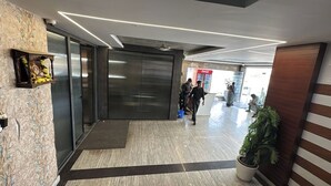 A modern lobby with a reception desk, a Coca-Cola refrigerator, and a potted plant. - Hotel SN Grand (Maheshwaram)