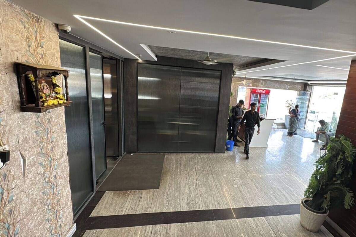 A modern lobby with a reception desk, a Coca-Cola refrigerator, and a potted plant.