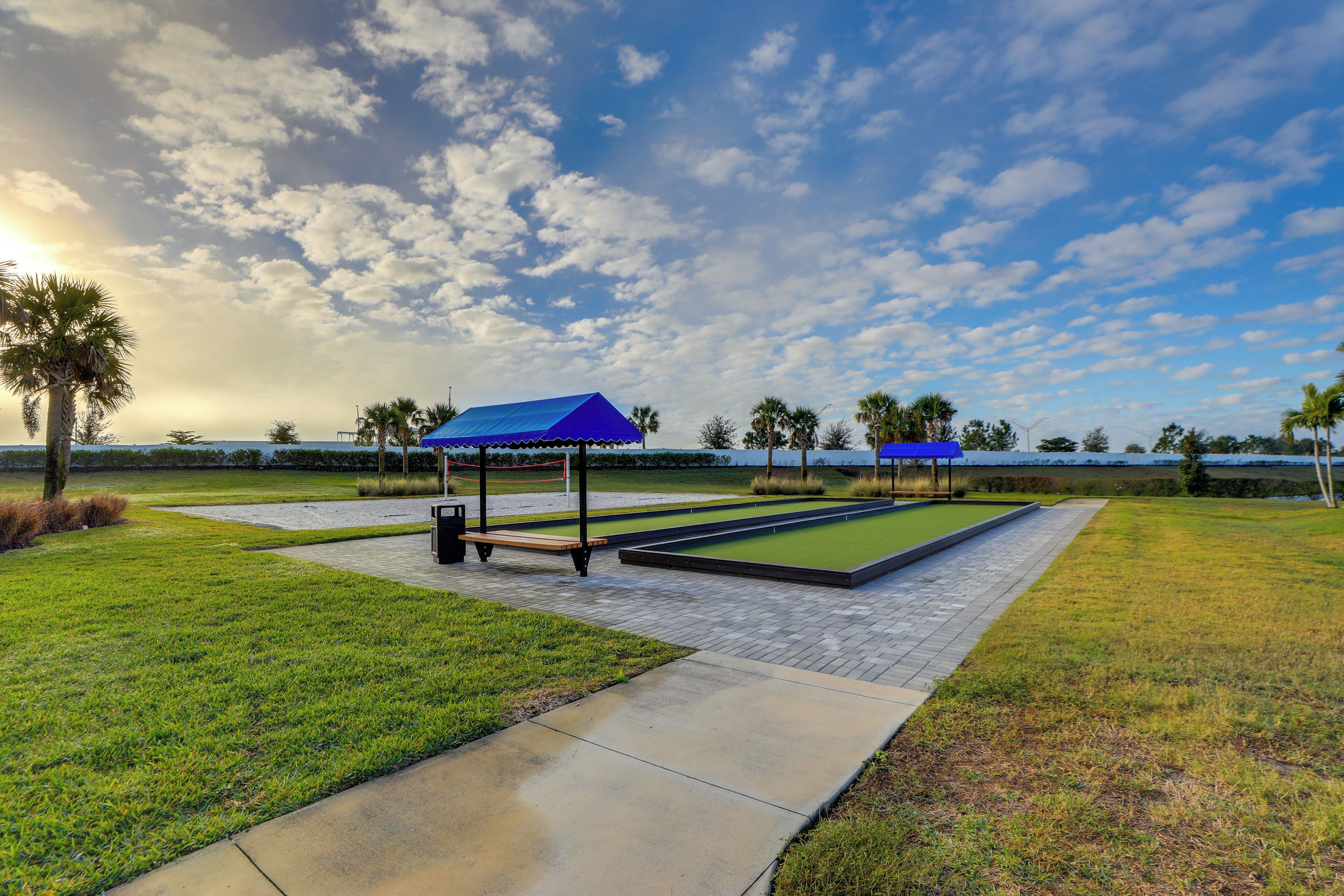 A pool table area with a blue-roofed pavilion, surrounded by well-maintained grass and a clear sky.
