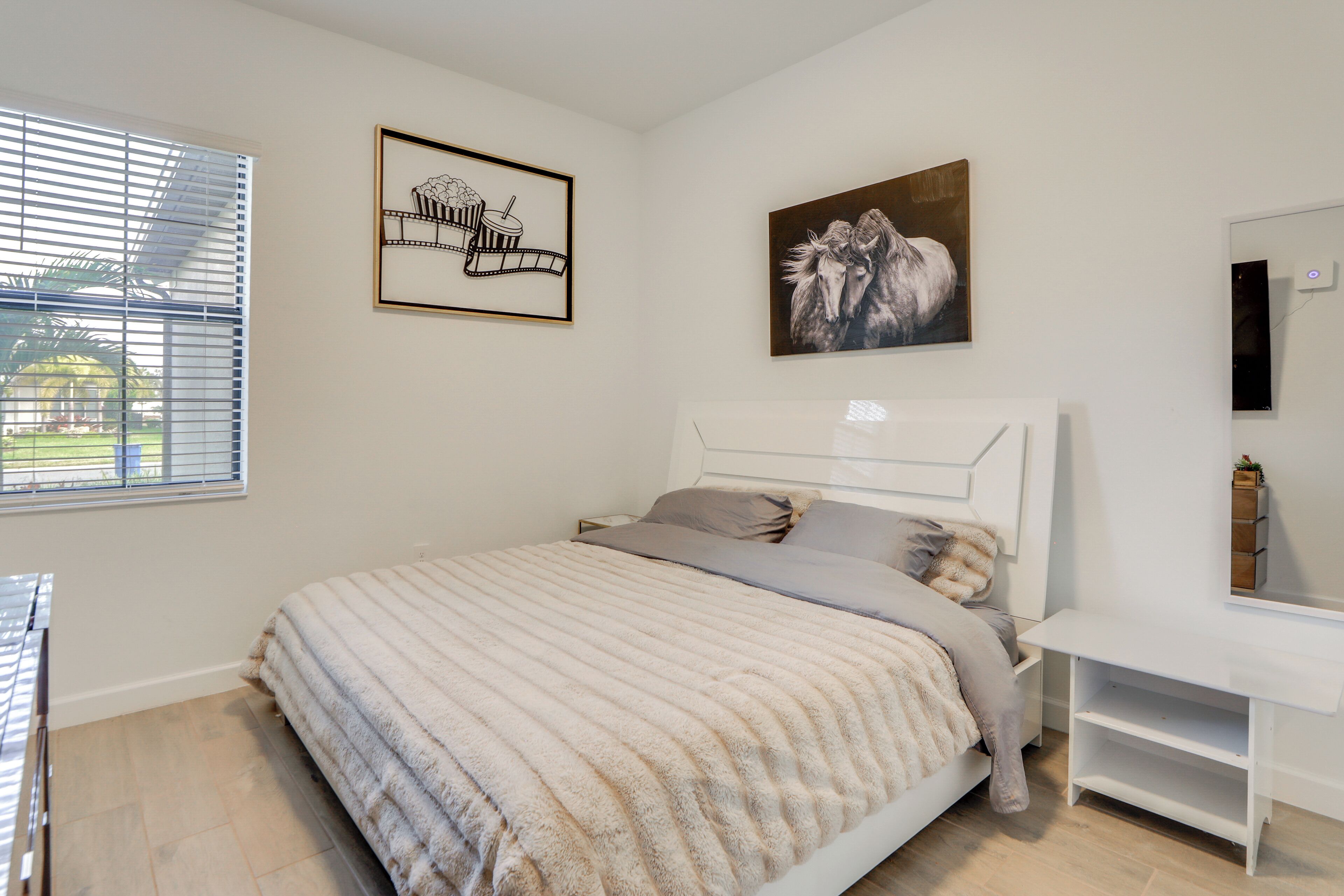 A bedroom with a bed, a nightstand, a dresser, and a window with blinds.