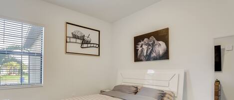 A bedroom with a bed, a nightstand, a dresser, and a window with blinds.