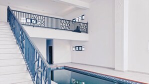 A modern indoor pool with a blue railing and a clear view of the water. - Bee-City Apartment (Abuja)