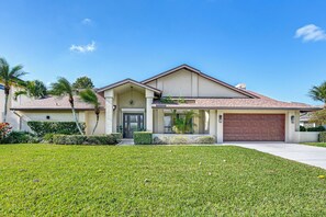 A modern two-story house with a front garage, a well-maintained lawn, and palm trees. - Golf Course View, Pool & Lanai! Upscale Naples Gem (Naples)