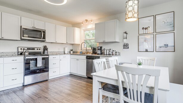 A modern kitchen with white cabinets, stainless steel appliances, and a dining area with a white table and chairs. - 1 Mi to Park Circle: Pet-Friendly Home w/ Yard (North Charleston)