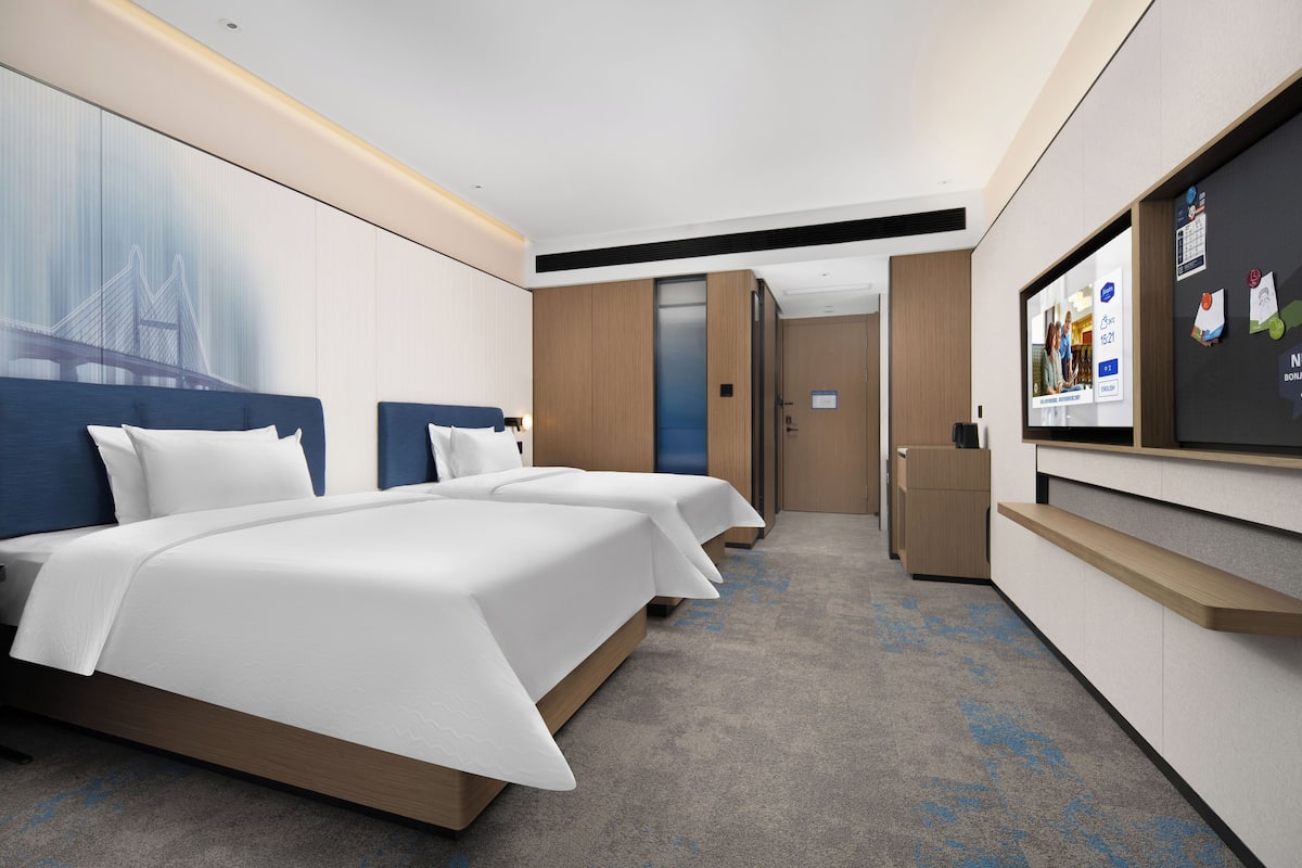 A hotel room with two beds, a TV, and a desk.
