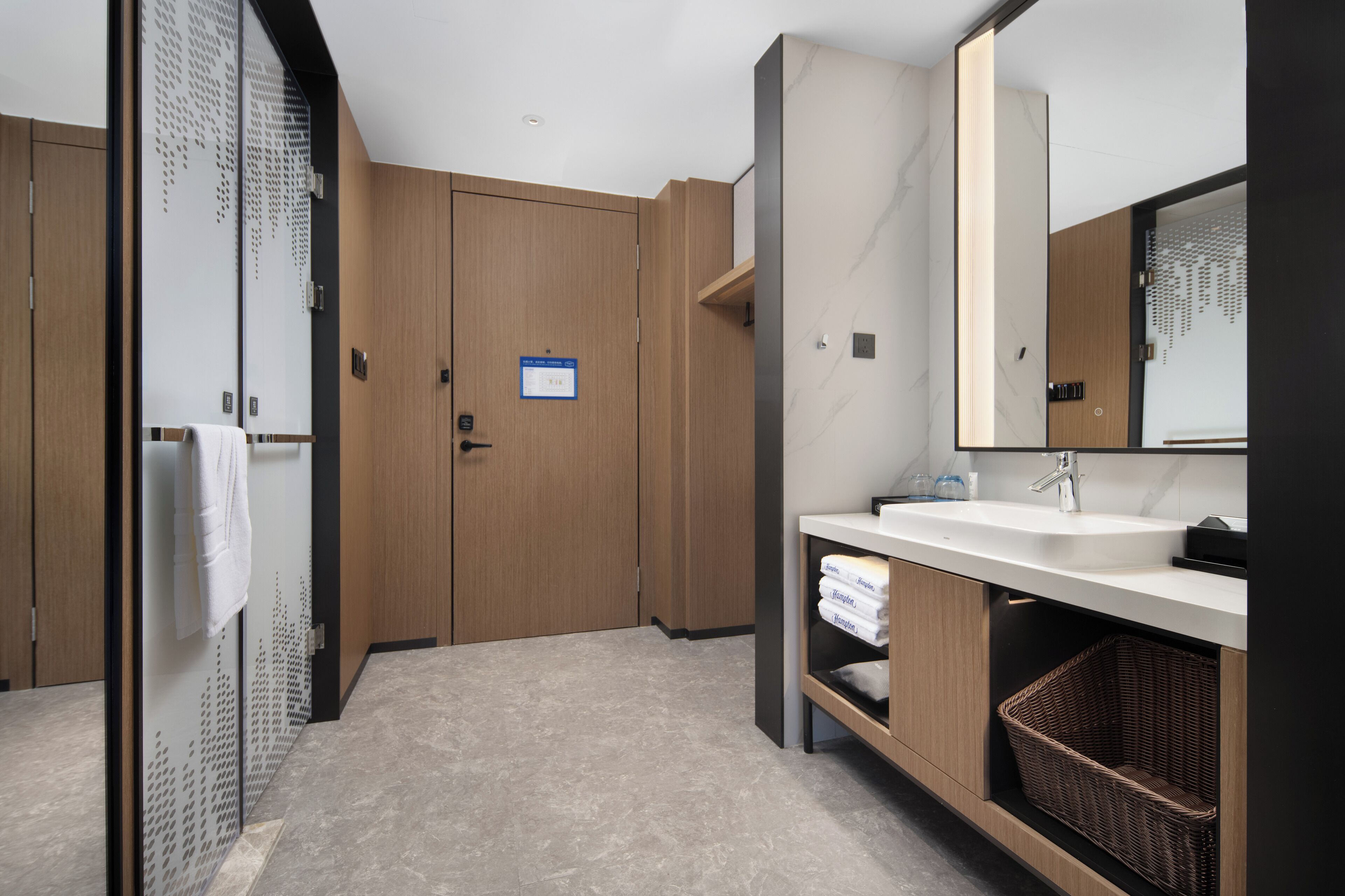 A modern bathroom with a large mirror, wooden cabinets, a sink, and a towel rack.
