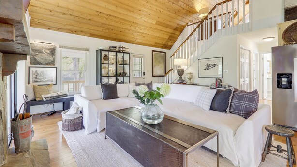 A spacious living room with a high wooden ceiling, a staircase, and a large window. - Wilderness Retreat on Crooked Creek, Lake Sinclair (Eatonton)