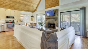 A modern kitchen with stainless steel appliances, a large island, and a stone fireplace. - Wilderness Retreat on Crooked Creek, Lake Sinclair (Eatonton)