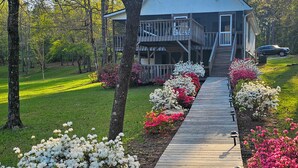 A two-story building with a wooden deck leading to a covered porch. - Wilderness Retreat on Crooked Creek, Lake Sinclair (Eatonton)
