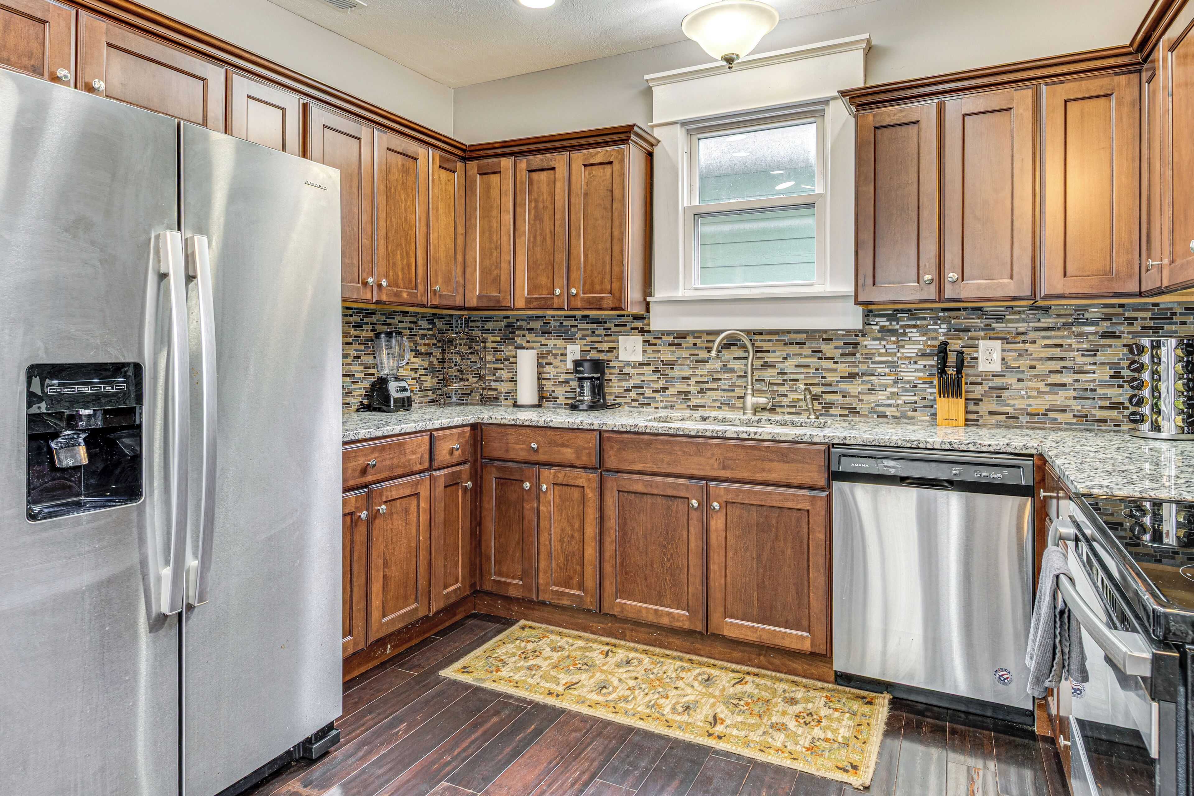 A kitchen with wooden cabinets, stainless steel appliances, and a tiled backsplash.