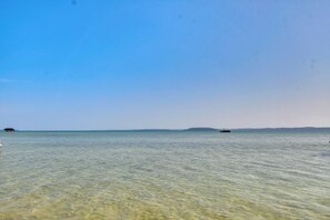 A clear view of a calm sea with a distant landmass and a boat. - New Home on Lake Michigan's Traverse City West Bay (Traverse City)