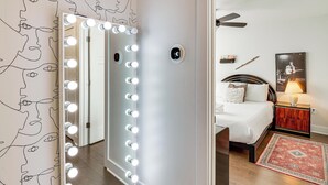 A room with a vanity mirror with lights, a bed with a headboard, a nightstand with a lamp, and a wall with a framed picture. - 6 Mi to Broadway: Nashville Townhome w/ Balcony! (Nashville)