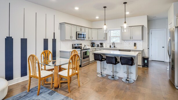 A modern kitchen with a central island, bar stools, wooden chairs, and a dining table. - 6 Mi to Broadway: Nashville Townhome w/ Balcony! (Nashville)