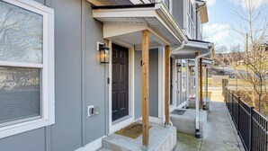 A residential building with a gray exterior, a black front door, and a covered porch with wooden columns. - 6 Mi to Broadway: Nashville Townhome w/ Balcony! (Nashville)